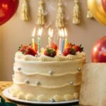 Birthday cake with candles, balloons, and festive decorations.